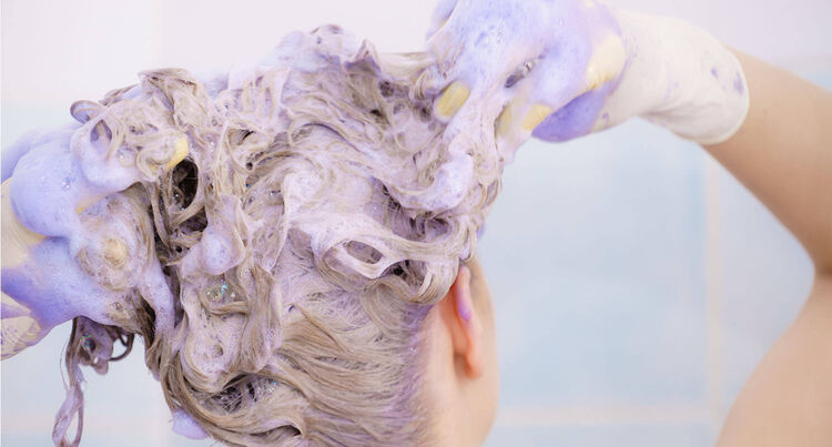 achterkant van het hoofd van een vrouw die haar wast met paarse zeep