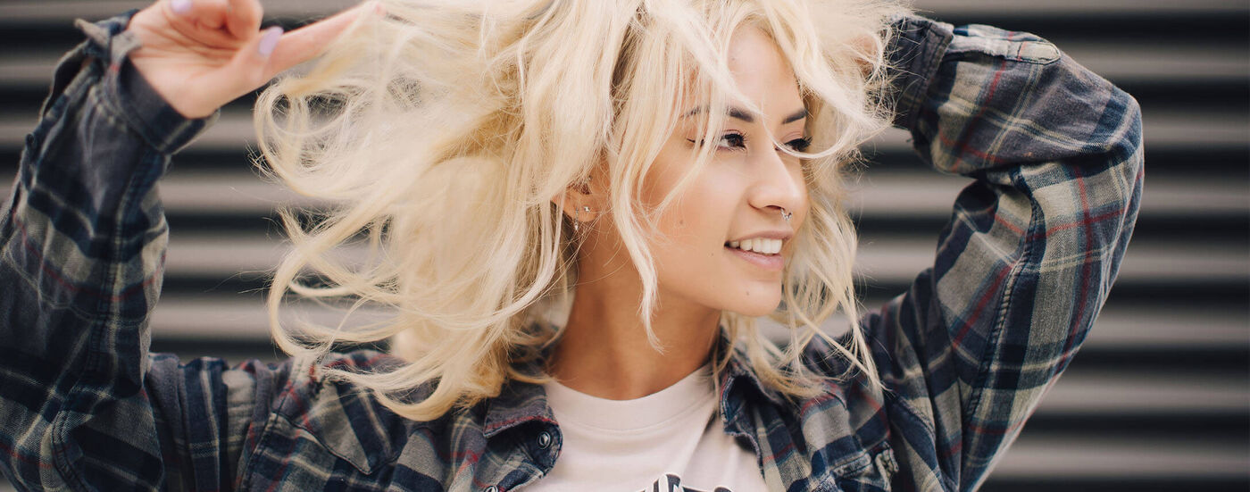 voorkant van het hoofd van een vrouw die met haar vingers door haar blonde haar gaat
